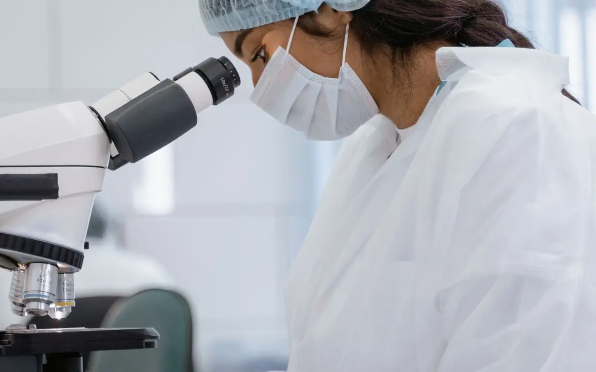 Technicienne de laboratoire observant un échantillon au microscope